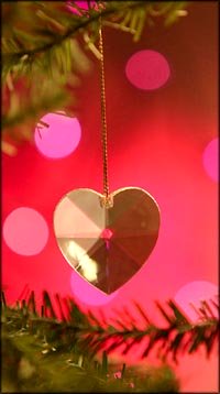 Warm Christmas quotes on love: Golden Christmas heart hanging on Christmas tree.