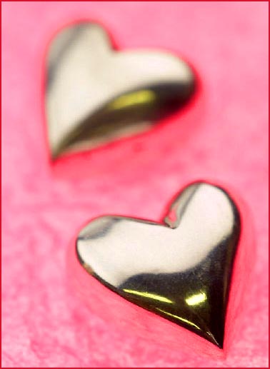 Love: picture of two silver hearts on pink velvet.