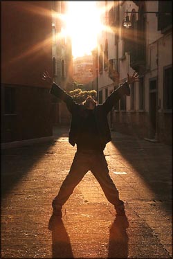 Motivational quotes: Man with arms out in the sunset seizing the world.