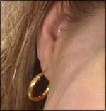 Woman's ear and golden earring.