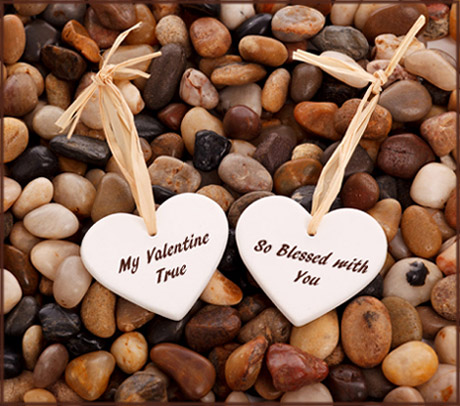 Free Valentines to print: Photo of two small white hearts with Valentines poems lying on small pebbles. 