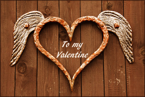 Beautiful Valentine Pictures: Photo of iron heart with white wings hanging on brown wooden boards.