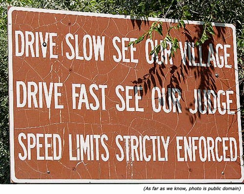 Hilarious traffic sign: A funny town sign saying: Drive slow see our village! Drive fast see our judge! Speed limits strictly enforced!