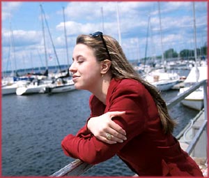 Happy birthday messages: Woman closing her eyes and enjoying the moment by the sea.