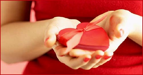 Love hearts photo: Picture of woman holding a red heart in both her hands.