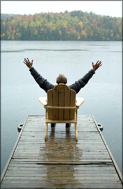 Being thankful for life: Man sitting in a chair on a small bridge with his arms out to the side.